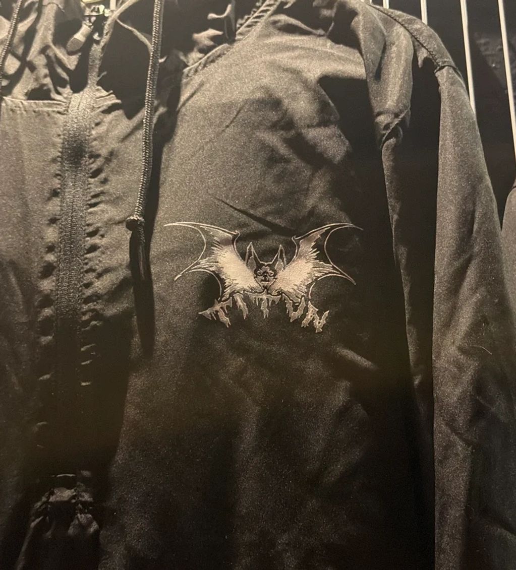 Black jacket with a detailed bat emblem on the chest.