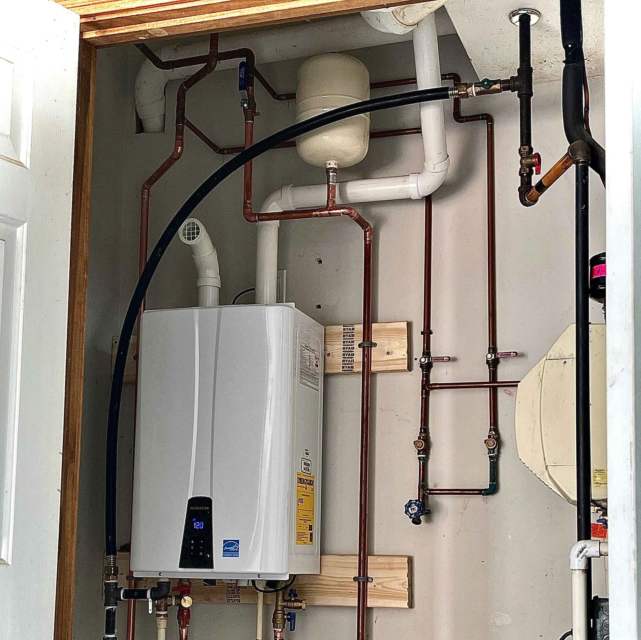 Modern gas water heater with pipes in a utility closet.