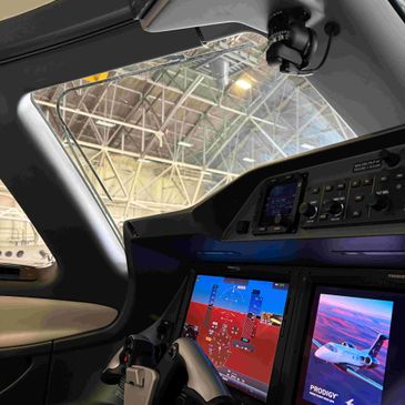 Cockpit view of a modern aircraft with digital displays inside a hangar.