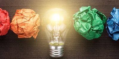 Crumpled balls of paper in red, orange, green, and blue with a light bulb in the center.