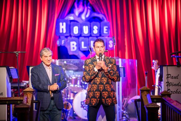 Two men on stage at House of Blues with red curtains.