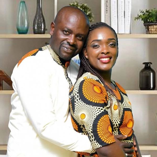 Smiling couple in matching traditional attire posing warmly indoors.