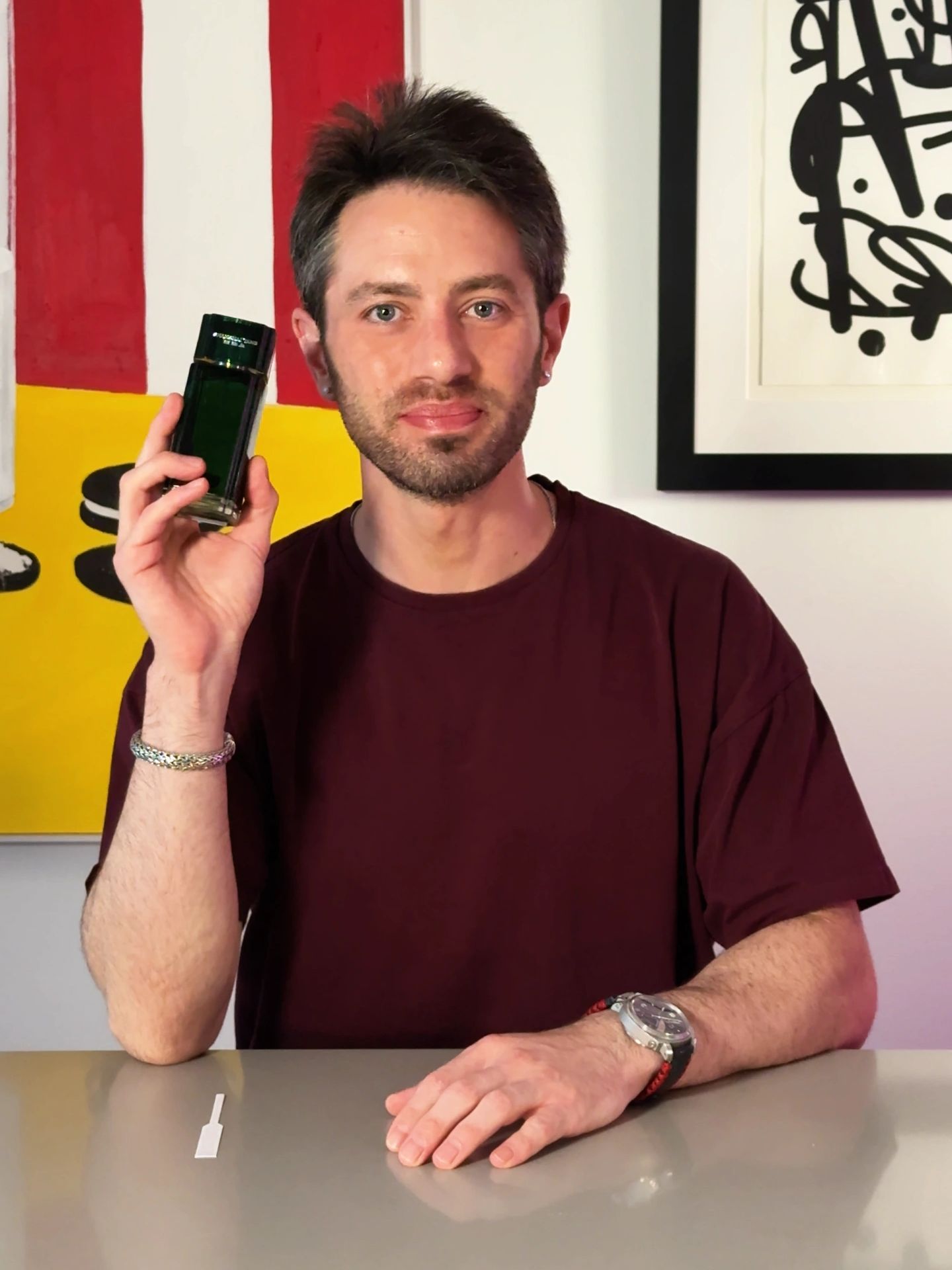 Steven Morse holding a fragrance bottle during a review video in his Miami studio