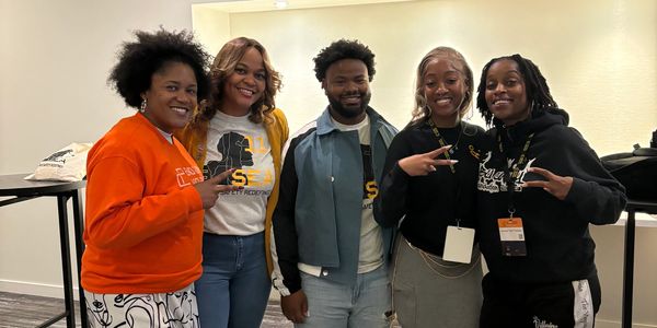 Group of five people smiling and posing indoors.