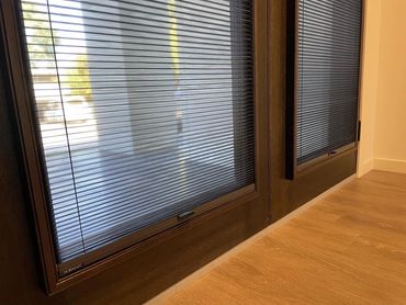 Close-up of window blinds with sunlight filtering through onto a wooden floor.