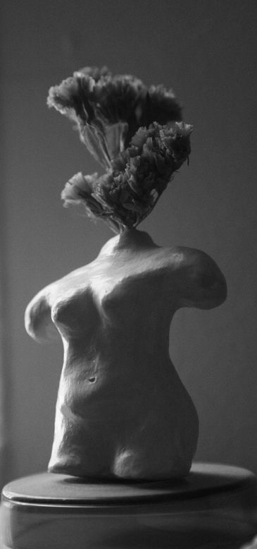 Sculpture of a female torso with flowers as a head in black and white.