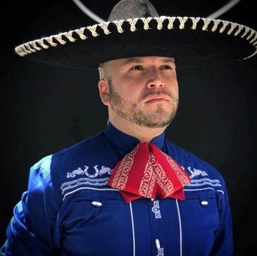 A man wearing a traditional Mexican charro outfit with a large black sombrero.