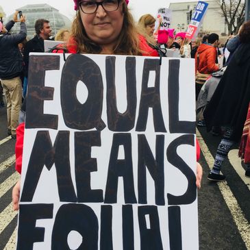Person holding a protest sign that says 'Equal Means Equal'.