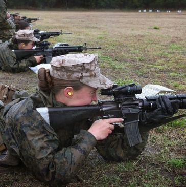 Military personnel aiming rifles while lying on the ground during training.