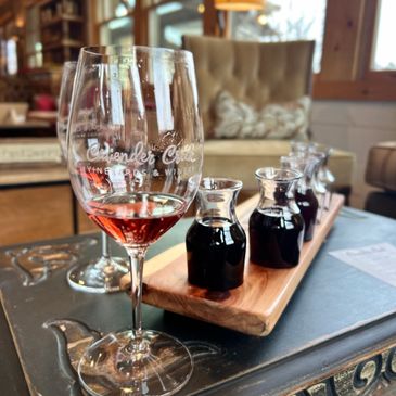 Wine tasting setup with glasses and small pitchers on a wooden board.