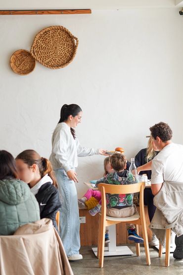 Woman serves a child at a table in a cafe.