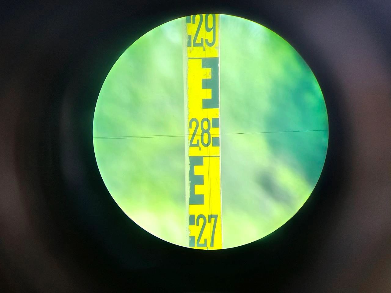 Yellow levelling staff viewed through a survey level telescope, aligned with the crosshairs.