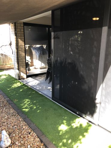 Backyard patio with artificial grass and rocks.