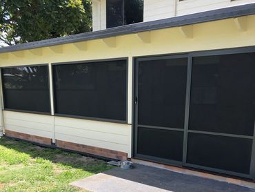 Exterior view of a building with large black mesh screens on windows and door.