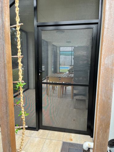 Sliding glass door with a mesh screen and wooden frame.