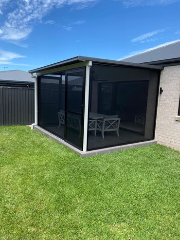 Modern patio with mesh enclosure and grass lawn.