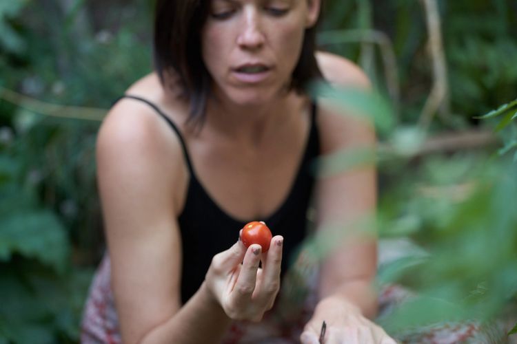 flow and food Yoga Canberra owner Tracey picking a tomato in her garden