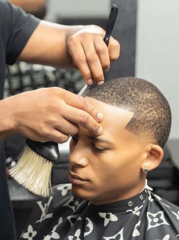 Barber shaping a man's hairline with precision.