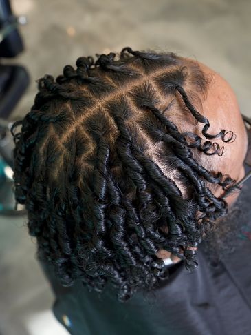 Close-up of neatly twisted and parted natural hair on a person's head.