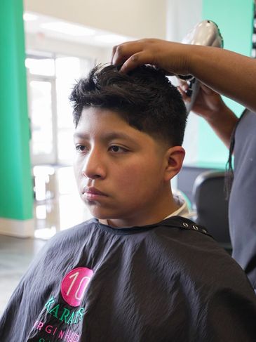 Young boy getting a haircut in a barber shop.