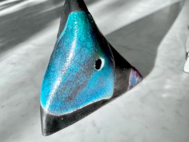 Blue and black ceramic object with a hole.