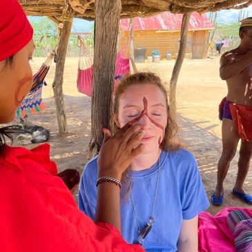 Wayuu woman painting the face of a traveler with her traditional symbols