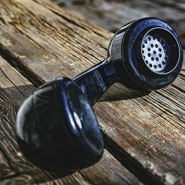 Old-fashioned telephone handset on a distressed wooden tabletop.