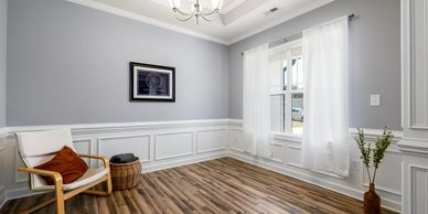 Minimalist room with wooden floor, white chair, and soft gray walls.