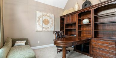 Elegant home office with wooden desk and bookshelf.