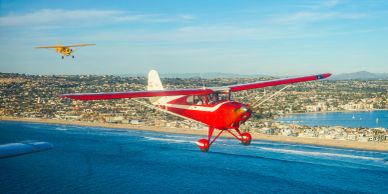 Two small planes flying over a coastal city.