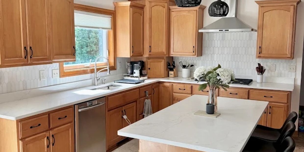 Modern kitchen with wooden cabinets and marble countertops.
