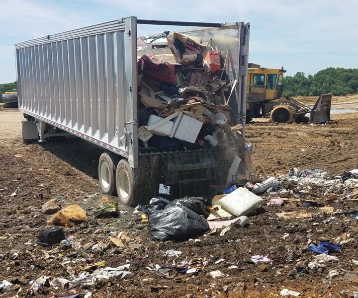 Dump truck unloading trash at landfill.