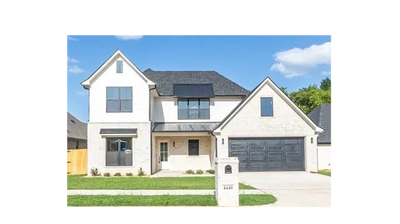 Modern two-story house with white brick exterior and black roof.