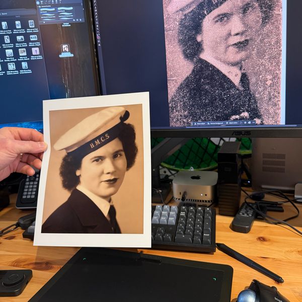 Restoring a vintage photo of a woman in HMCS uniform on a computer.