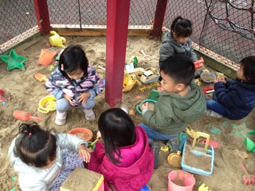 group of children playing in the sandbox within the playground at the daycare