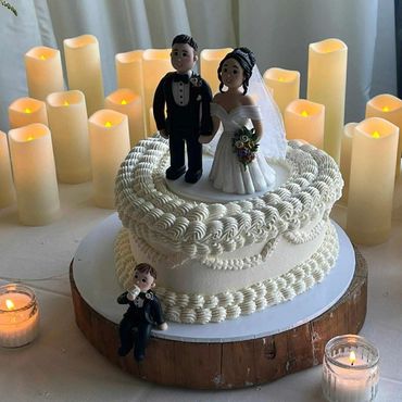 Wedding cake with bride and groom figurines surrounded by candles.