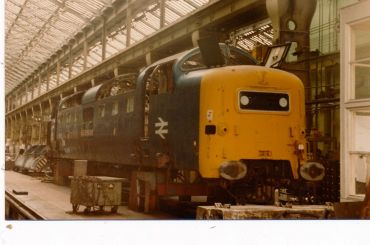 Vintage yellow and blue train engine in a spacious workshop.