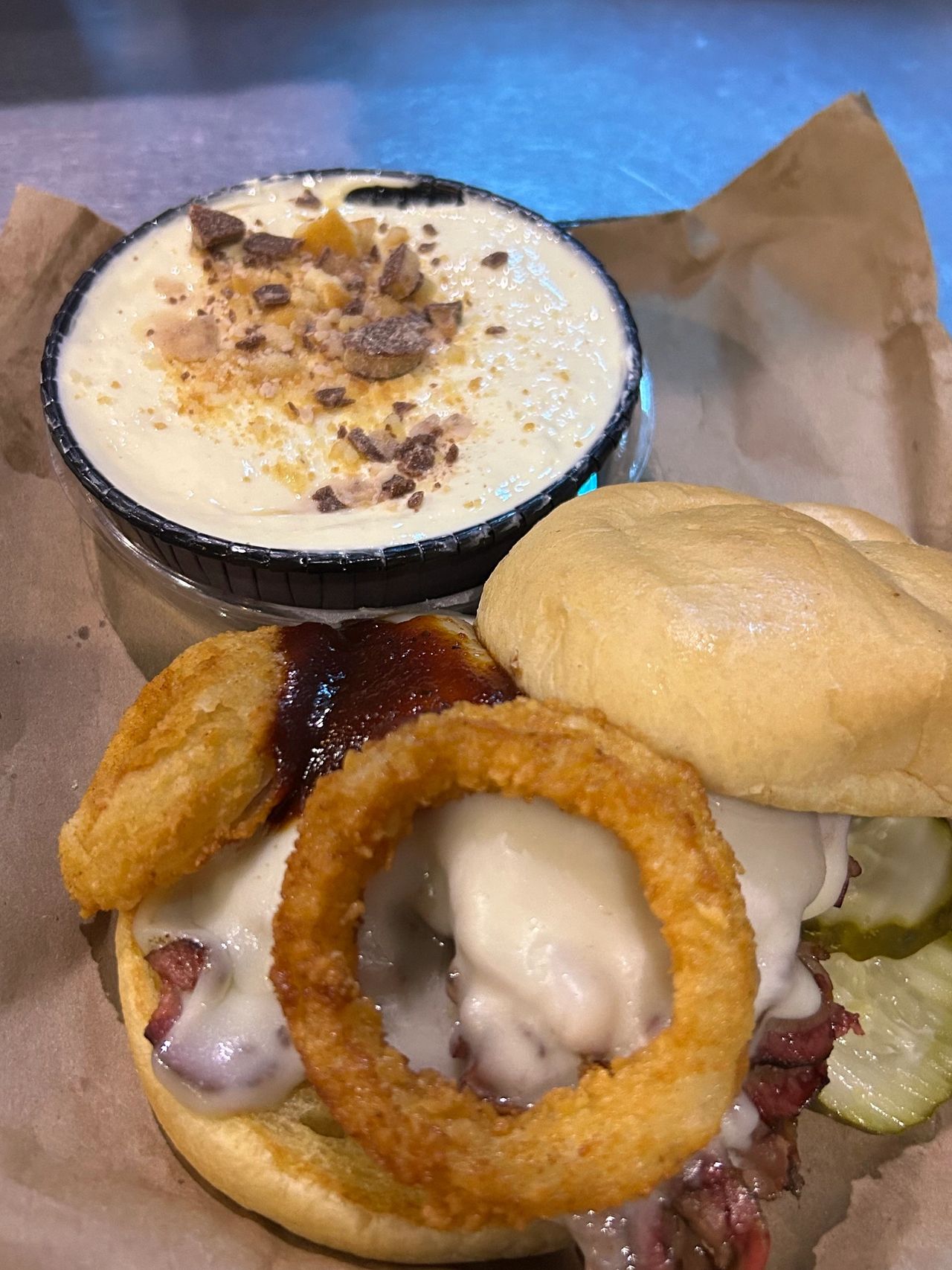 The world famous Z-Man sandwich from Joe's Kansas City BBQ. Topped with smoked provolone cheese and an onion ring, this beef brisket sandwich is legendary. Also pictured is the amazing banana pudding dessert topped with Heath bar.