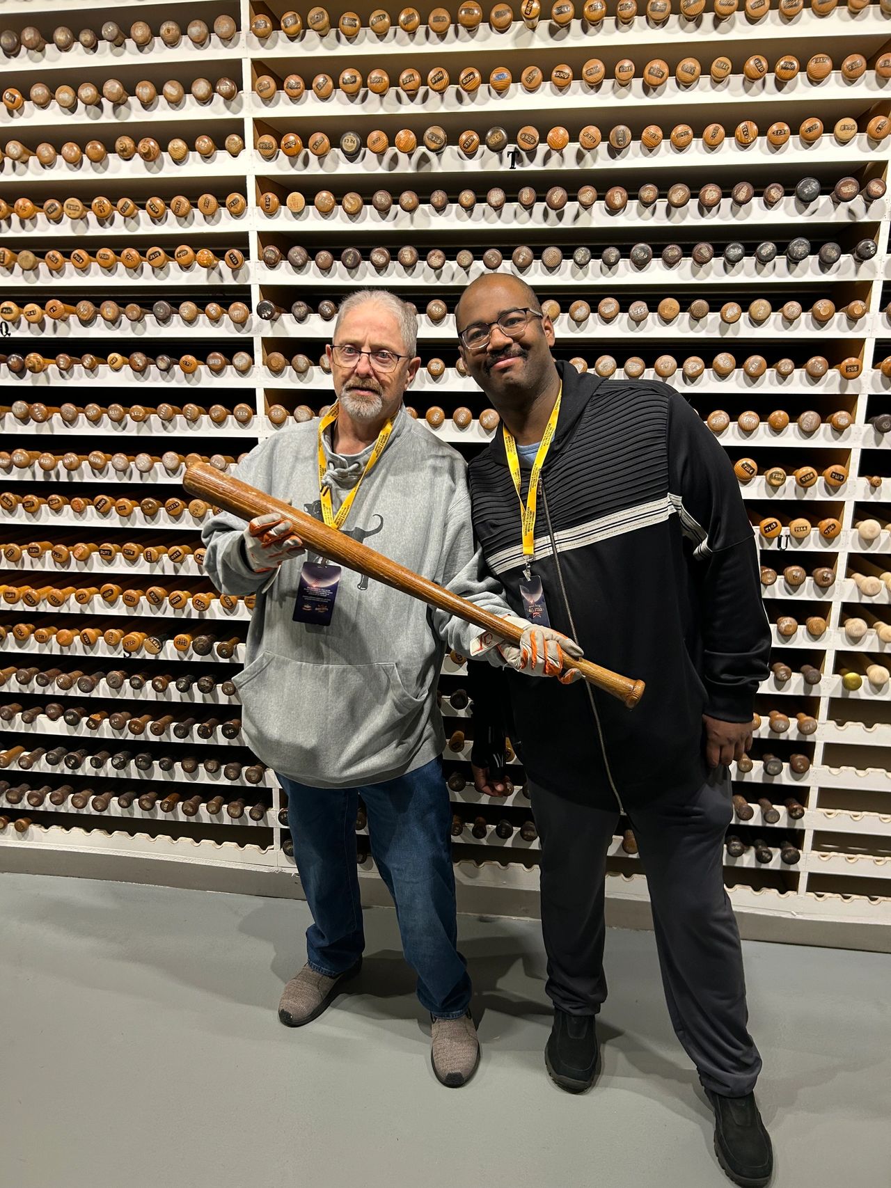 Two men holding a Jackie Robinson model game-used bat inside the historic Bat Vault at the Louisville Slugger Museum & Factory