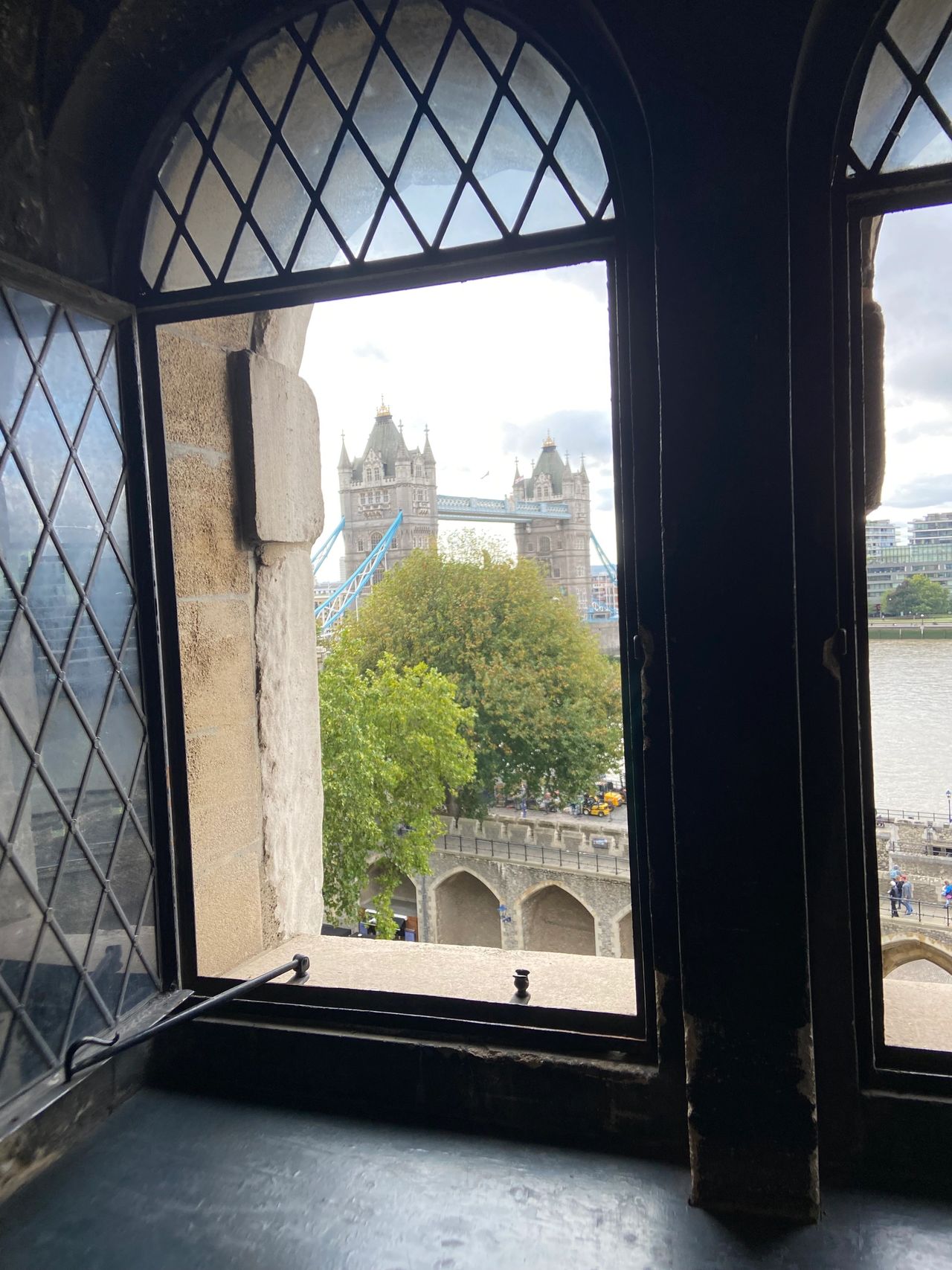 One of the windows in the Tower of London, providing a beautiful view of the London skyline and the Tower Bridge.