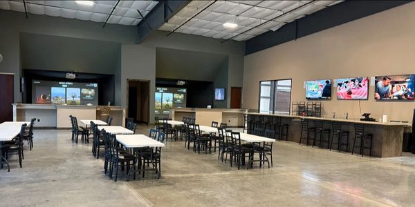 Spacious modern dining area with tables, chairs, and multiple TV screens.
