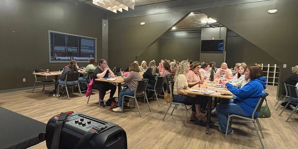 People gathered in a room sitting at tables, engaged in conversation.