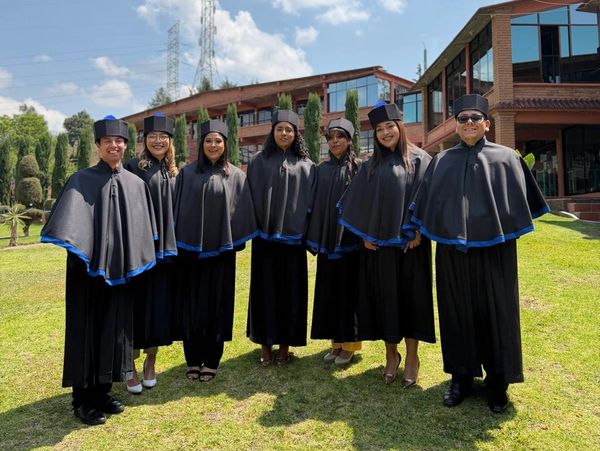 Grupo de graduados con togas y birretes al aire libre.