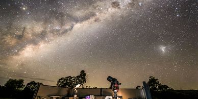 Telescope under a stunning star-filled night sky with the Milky Way.