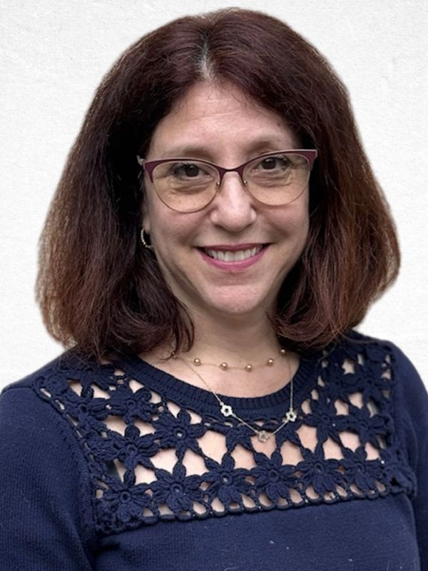Woman with glasses smiling, wearing a navy blue top with floral lace design.