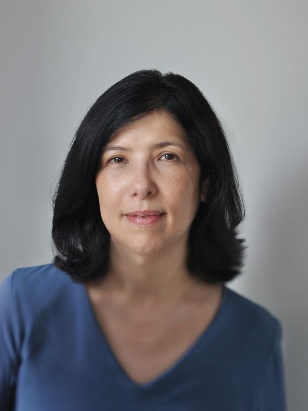 Portrait of a middle-aged woman with black hair wearing a blue top.