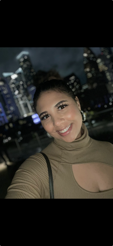 Smiling woman taking a selfie at night with city lights in the background.