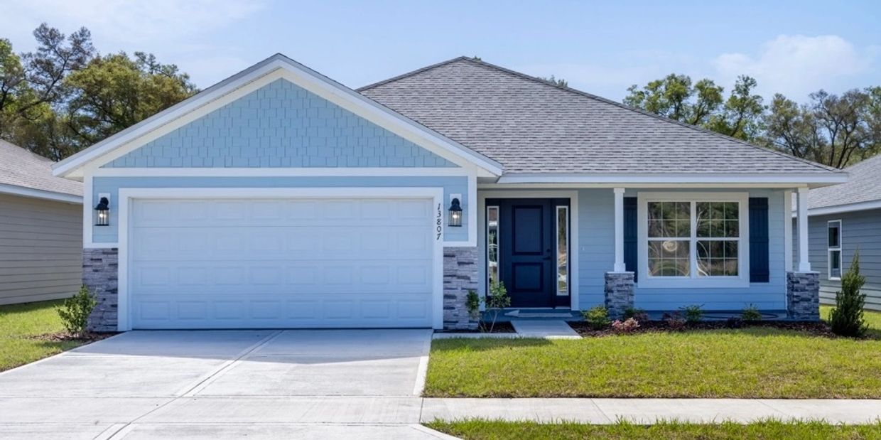 Modern blue house with a two-car garage and a manicured lawn.