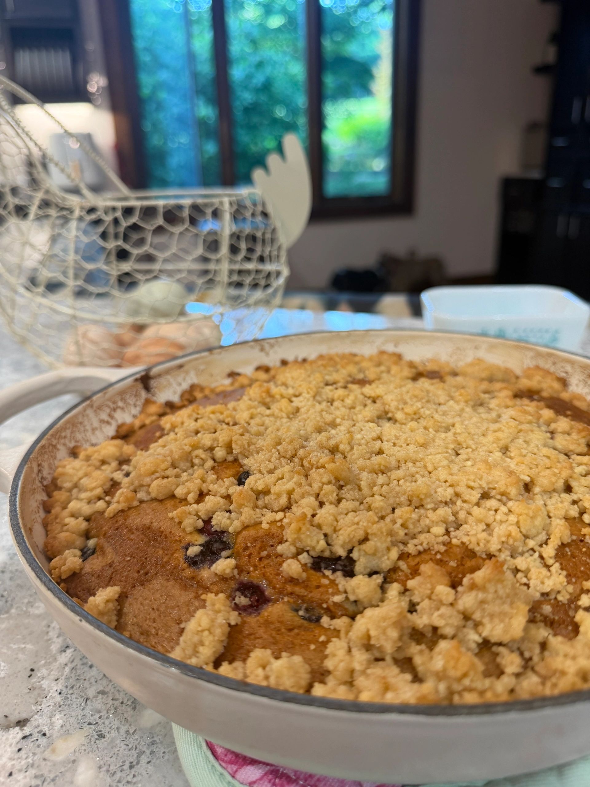 Close-up of a crumb-topped baked dessert on a table near a window.