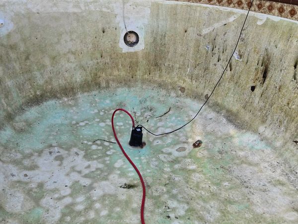 Empty, dirty pool with some cables inside.